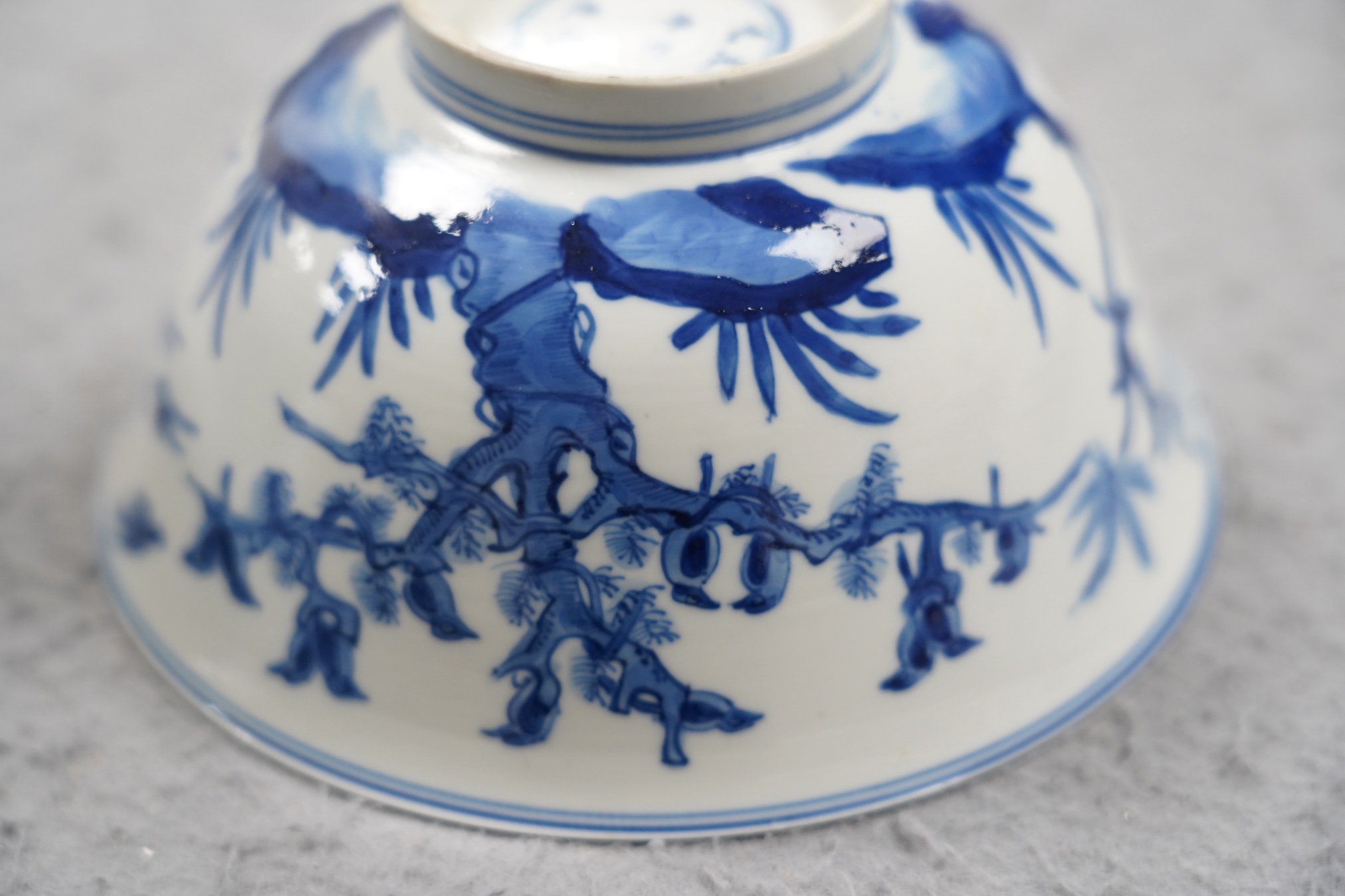 A near pair of Chinese blue and white ‘birds’ bowls, Kangxi period, one bowl restored